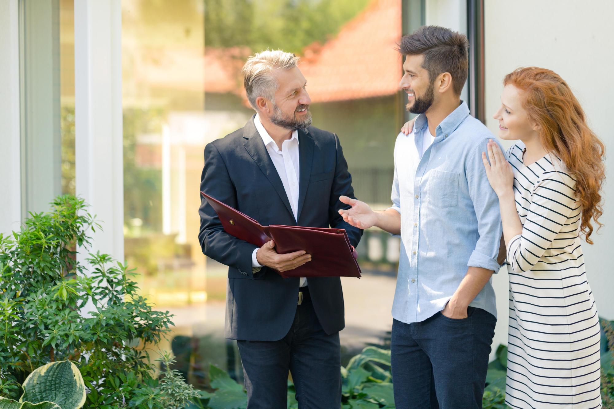 Agent imobiliar discutând cu proprietarul lângă proprietate